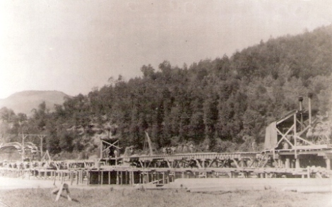  Milochov, montáž mosta. Zasúvacia drevená dráha ponad Váh, parné lokomobily pod prestrešením, vzadu zmontované most. pole. Foto: M. Stern, 1883. 127 x 90. Repro: Grófová 