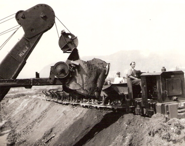  Lyžica lanového bagra, plechové huntíky. Vpredu motor. rušník. V pozadí kopec. Anon., cca 1950. 160 x 125 