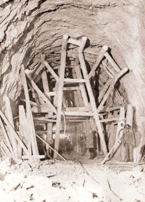  Hrubo vyrazený tunelový otvor v celom profile s výdrevou. Pózujúci robotníci a dozor. Text: Čachtice - tunel, ľahké vydrevenie. Anon., cca 1925. 130 x 90, repro: R. Rebro 