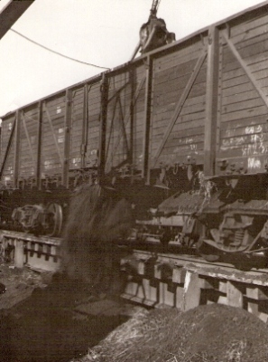  Štvornápravový vysokostenný vozeň s podlah. klapkami pri vykládke sypkého substrátu na výsypnej rampe v Čiernej nad Tisou. Anon., cca 1955. 116 x 144 
