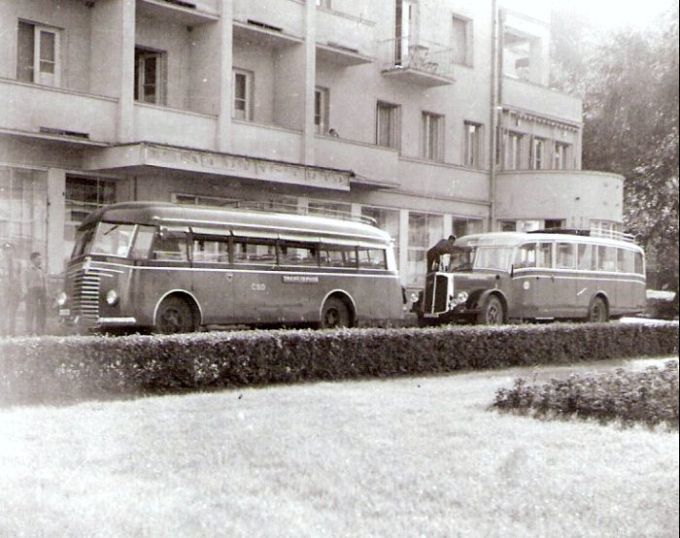  Pohľad zpredu na dva autobusy (predný neurč., zadný Saurer) s nápisom ČSD pred pošt. úradom v Tr. Tepliciach. Vľavo tri postavy (jedna v rovnošate). Anon., cca 1947. 100 x 96 