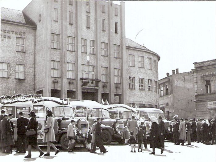  Ozdobené autobusy (Praga RND a Saurer) s plagátmi dvojročnice pred Mestským domom v Čadci.Mnoho ľudí v civile. Anon., cca 1947. 100 x 100 