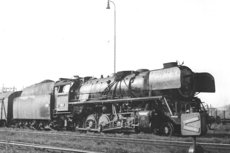  Parný rušeň 556.0112 + Ztr v žst. Hlohovec. Pohľad zprava zpredu. Vpravo vpredu výhybk s hranatým návestidlom. Osvetľ. stožiare. Foto: B. Danko, cca 1970. 148 x 104 