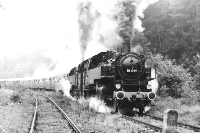  Parné rušne 86 (049 a ešte jeden) DR s osobným vlakom z podvozkových vozňov. Pohľad zprava zpredu. Les, vľavo druhá koľaj. Foto: M. Fogl, cca 1985. 148 x 105 
