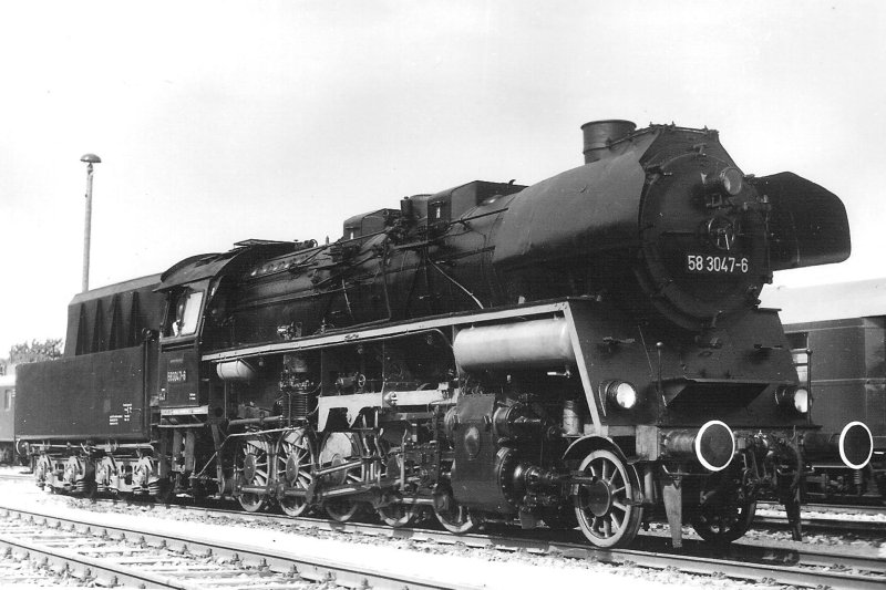  Parný rušeň 58 3047-6 DR v depe Erfurt West. Pohľad zprava zpredu. Vpravo vzadu historický štvornápravový vozeň DR. Foto: Anon., 6.6.1982. 123 x 84 