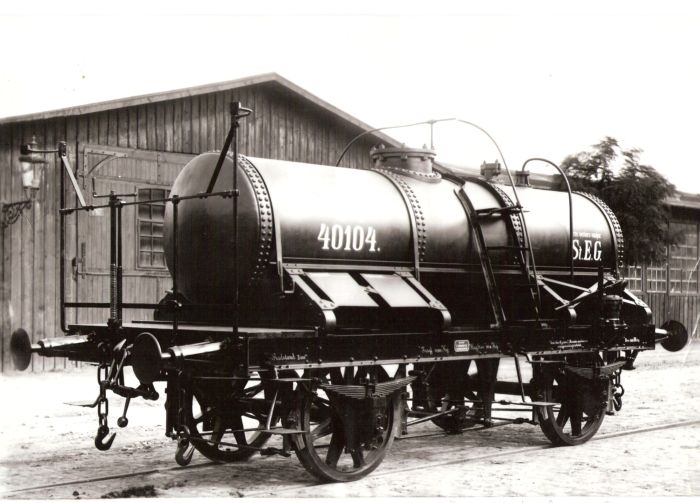  Nákladný dvojnápravový kotlový vozeň StEG zrejme vo vagónke Ringhoffer. Pohľad predobočný. Vzadu drevené haly, petrolej. lampa na konzole. Foto: Anon., cca 1888. 297 x 193 