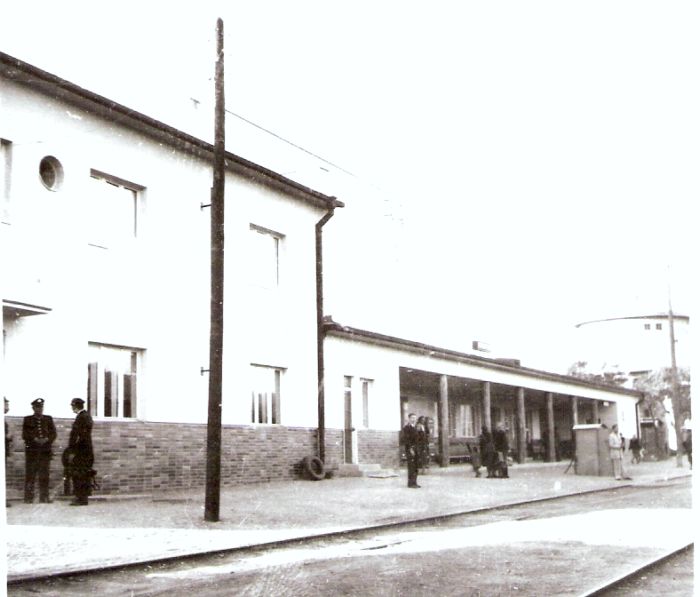  Krupina - výpravná budova nová. Šikmý pohľad zo strany koľají od Šiah. Vpravo vzadu vodáreň, vľavo dvaja železničiari a stavadlový kozlík. Foto: Anon., cca 1950. 98 x 95 