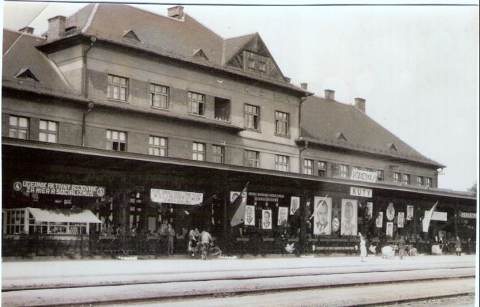  Kúty - výpravná budova nová. Šikmý pohľad zo strany koľají od Bratislavy. Výzdoba k 1. máju. Foto: Anon., cca 1950. 122 x 121 