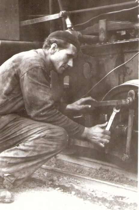  Muž v pracovnom odeve a baretke s kľúčom pri pojazde úzkorozchodného parného rušňa. Foto: Anon., cca 1950, zb. P. Faturu, Ladce, fotokópia 84 x 135 