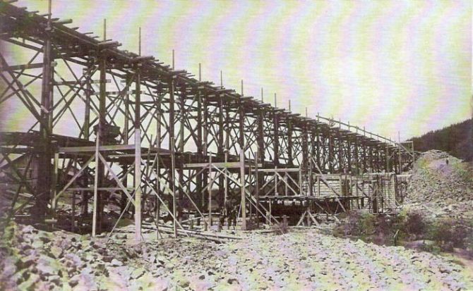  Veľké drevené lešenie, mostné piliere v stavbe. Text: Výstavba trate Zvolen - Krupina. Foto: Anon., cca 1923, farebná xerokópia. 145 x 90 