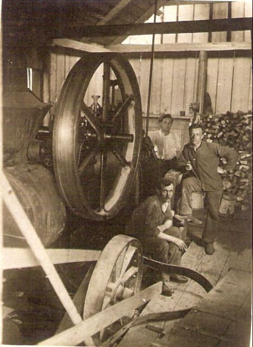  Parná lokomobila pod prístreškom, traja strojníci, při zadnej stene zložené palivové drevo. Text: Výstavba trate Zvolen - Krupina. Foto: Anon., cca 1923, farebná xerokópia. 84 x 112 