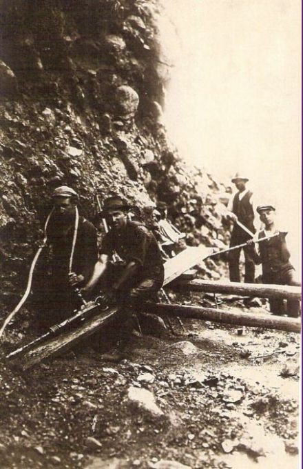  Ľudia v záreze pri vŕtaní dier pneumatickou vŕtačkou. Text: Výstavba trate Zvolen - Krupina. Foto: Anon., cca 1923, farebná xerokópia. 90 x 140 