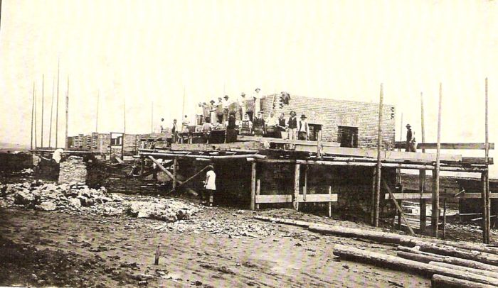  Rozostavaná budova. Múry s okennými otvormi, drevené lešenie. Pózujúci ľudia v krojoch a civile. Text: Výstavba trate Zvolen - Krupina. Foto: Anon., cca 1923, farebná xerokópia. 140 x 86 