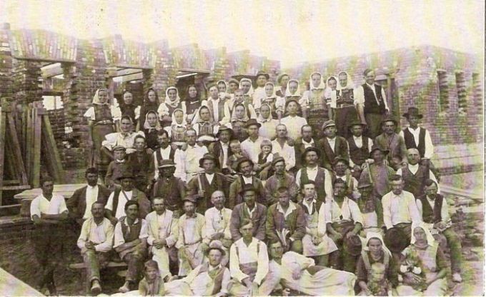  Skupinová fotografia robotníkov - mužov i žien - v pracovnom i krojoch pred rozostavanou budovou. Text: Výstavba trate Zvolen - Krupina. Foto: Anon., cca 1923, farebná xerokópia. 139 x 89 