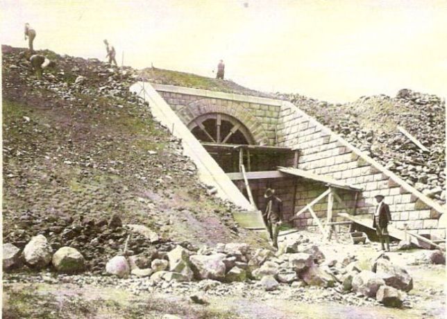  Kamenný železničný most v stavbe. V klenbe sú skruže. Ľudia pracujú na dohotovovanom násype. Text: Výstavba trate Zvolen - Krupina. Foto: Anon., cca 1923, farebná xerokópia. 112 x 83 