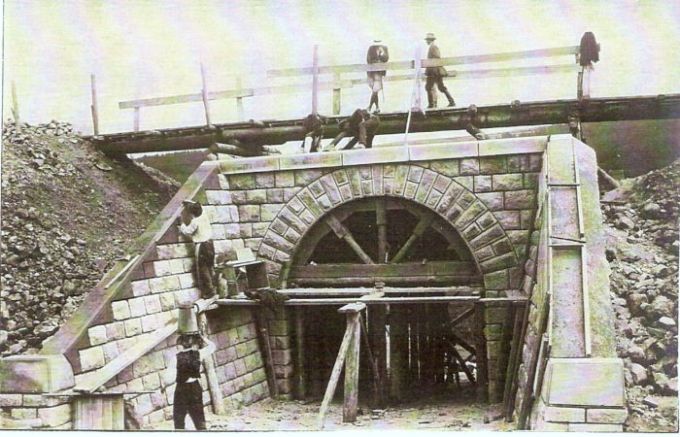  Kamenný železničný mostík v stavbe. Dokončovacie murárske práce. Nad klenbou provizórne drevené premostenie. Text: Výstavba trate Zvolen - Krupina. Foto: Anon., cca 1923, farebná xerokópia. 140 x 88 