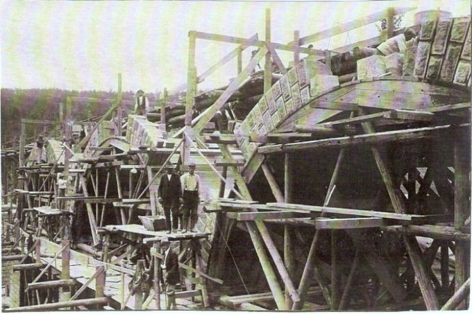  Veľké mostné kamenné klenby v stavbe. Drevené lešenie, vzadu les. Ľudia pri práci. Text: Výstavba trate Zvolen - Krupina. Foto: Anon., cca 1923, farebná xerokópia. 142 x 95 