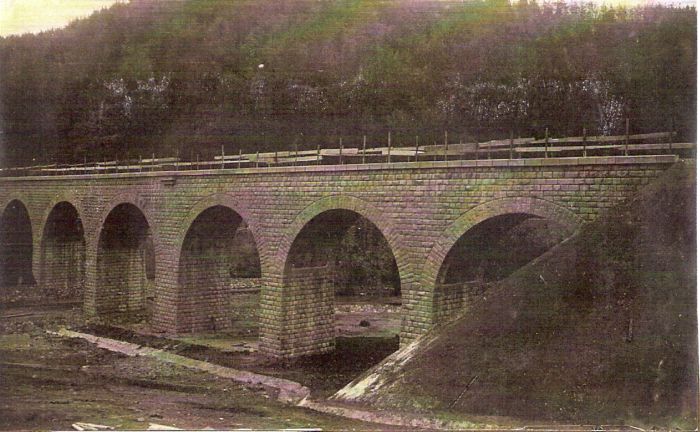  Dohotovený kamenný most. Pohľad zboku. Vzadu zalesnený kopec. Text: Výstavba trate Zvolen - Krupina. Foto: Anon., cca 1923, farebná xerokópia. 144 x 90 
