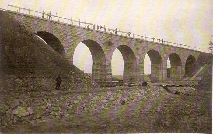  Dohotovený kamenný most. Pohľad zboku. Dole regulovaný vodný tok. Na moste postávajú ľudia. Text: Výstavba trate Zvolen - Krupina. Foto: Anon., cca 1923, farebná xerokópia. 143 x 90 