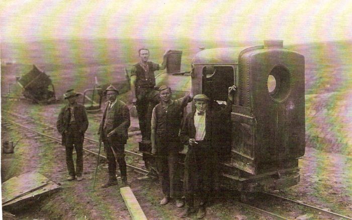  Úzkorozch. motorový rušeň. Vzadu pole a rozhádzané drevené huntíky. Pred rušňom pózujúci ľudia v civile. Text: Výstavba trate Zvolen - Krupina. Foto: Anon., cca 1923, farebná xerokópia. 139 x 87 