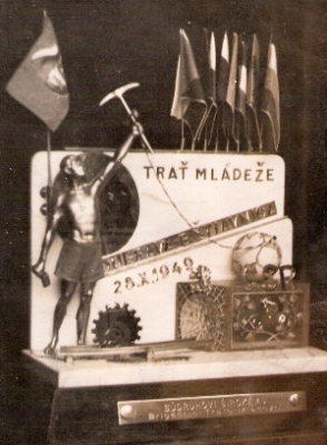  Upomien. predmet so soškou brigádnika, vlajkami, nápisom Trať mládeže 28.X.1949 a štítkom Súdruhovi Širokému brigádnici Trate mládeže. Anon., cca 1950. 154 x 118 