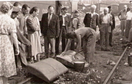  Veľká skupina ľudí v civile i rovnošatách sleduje ženu v pracovnom, ručne čiastiacu na koľaji pred vozňom Ba 3545 dve dvojice sedákov. Anon., cca 1960. 130 x 82 