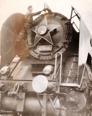  Čelo rušňa 476.001, muž v prac. so železn. čiapkou pri čistení znaku Škoda na dýmnici. Anon. cca 1955. 140 x 180 
