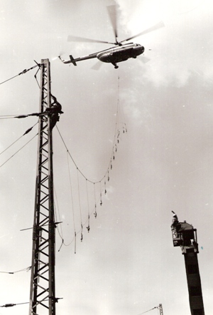  Spišská Nová Ves - rekonštrukcia trakč. vedenia v stanici. Vrtulník s podveseným lanom a závesmi, robotníci na trakčnej podpere. Foto: M. Meliška, cca 1977. 125 x 173 