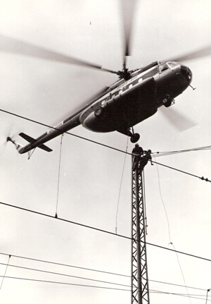  Spišská Nová Ves - rekonštrukcia trakč. vedenia v stanici. Vrtulník s podveseným lanom a závesmi, robotníci na trakčnej podpere. Foto: M. Meliška, cca 1977. 123 x 176 