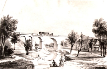  Most konskej železnice nad riečkou Gidra pri Báhoni - tehlový viadukt s os. vlakom (2 vozne, 2 kone). Husiar, dve ženy, dom, stromy (faximile). Anon., cca 1850., 290 x 188 
