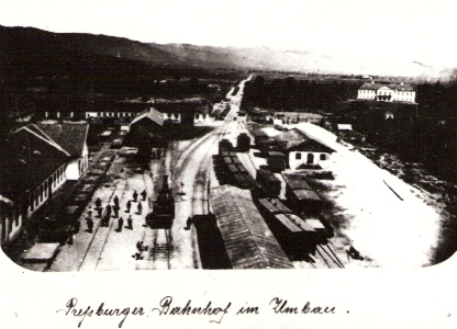  Pohľad z veže žst. Bratislava-Blumentál. Rušne, vozne, kryté nástupište, diel. budovy, sklady, Karpaty. Text: Pressburger Bahnhof im Umbau. Anon., cca 1873. 150 x 100 