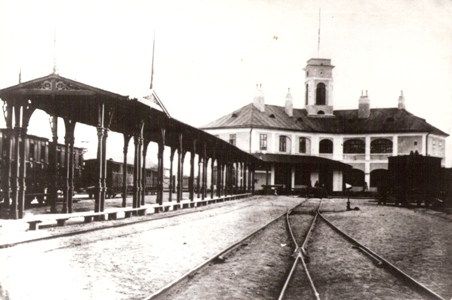  Stanica Bratislava-Blumentál - výpravná budova od koľajiska. Drevené kryté nástupište, dvojice vozňov konských vlakov, výhybka. Anon., cca 1873, 230 x 155 