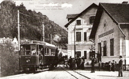  Stanica Trenčianske Teplice - priečelie výpravnej budovy a hotela Garni, motorový vozeň, trakč. podpera, ľudia. Anon., cca 1910, 130 x 85, repro: R. Rebro (Trenč. múzeum) 