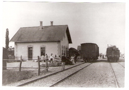 Rybany - výpravná budova, drevená ohrada, otvorené a kryté nákl. vozne, železničiar a ľudia v krojoch pri práci. Anon., 1901. 130 x 88. Repro: T. Grófová (Trenč. múzeum). 