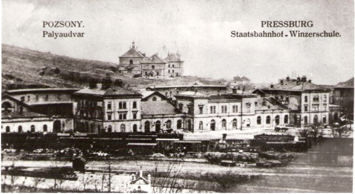  Bratislava hl. st. - pohľad na Feiglerovu výpravnú budovu a vinársku školu od Pražskej ul. cez koľajisko Dvor s nákl. vozň. Vzadu depo s 2 rotundami. Anon., cca 1900. 173 x 95 