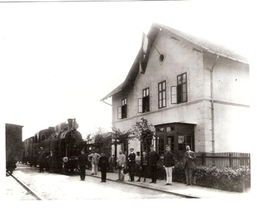  Vrbové - výpr. budova s uhorskou zástavou, koľajisko s komp. parným rušňom 331.0, nákladné vozne, pózujúci železničiari a civilisti. Foto: M. Klčo, cca 1910. 150 x 110 pred r. 1918 