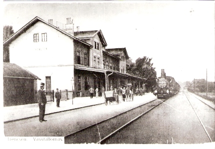  Trenčín - výpravná budova s markízou, koľajisko s vchádz. vlakom, drev. káry na batožinu, železničiari, civilisti. Č-b reprodukcia farebnej pohľadnice. Anon., 1914. 130 x 90, repro: T. Grófová 