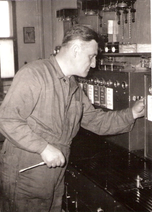  Muž v pracovnom pri riadiacom elektromech. prístroji (zrejme zo žst. Trnava) v dielni. Text: Člen BSP s. Šverčiča, OZ dielne Bratislava. Anon., cca 1960. 130 x 180 