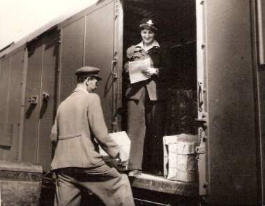  Žena v železn. rovnoš. stojí vo dverách zvlášt. vozňa s dvojicou posuv. dverí v jednej bočnici. Muž v civile jej podáva balík. Text: Manipulantka Jolana Smetanová chodí na trati Košice - Žilina - Bohumín a späť v žst. Košice. Anon., cca 1950. 109 x 84 