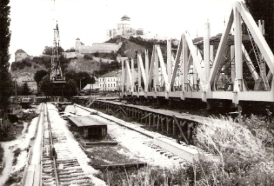  Stavenisko rekonštr. mosta cez Váh pri Trenčíne, pohľad na rozostavanú konštr. na trenčianskom brehu. Mont. žeriav a jeho dráha. Hrad. Text: Trenčín - rekonštrukcia železničného mosta. Foto: Gloss, V., 22.7.1983. 130 x 90 