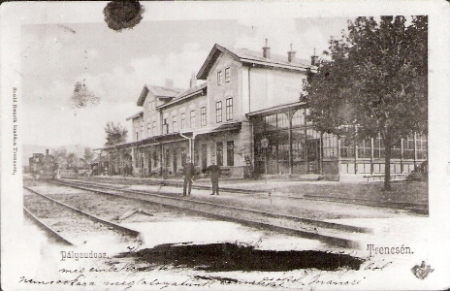  Trenčín - výpravná budova s markízou, drevená prístavba čakárne, na koľajisku v diaľke 310.4. Dvaja železničiari. Anon., cca 1910. 107 x 68 