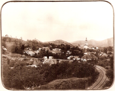  Obec Banská Belá s kostolom. V popredí ľavotočivý oblúk trate s dvoma drevenými mostami. V diaľke banskoštiav. kalvária. Foto: Kóczány, 1896. 225 x 175 