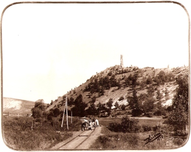  Pahork. krajina s jednokoľaj. traťou, dva protioblúky. Telegr. tyče, prechod. Civili pri úprave trati, práca s libelou. Zrúc. hradu. Text: Hrad Kanász. Foto: Kóczány, 1896. 225 x 175 