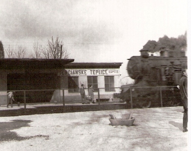  Turčianske Teplice - kúpele, budova zastávky, plot medzi koľajami. Zprava vchádza rušeň 456.0. Čakajúci ľudia. Anon., cca 1965. 130 x 90. Repro: V. Ammer 