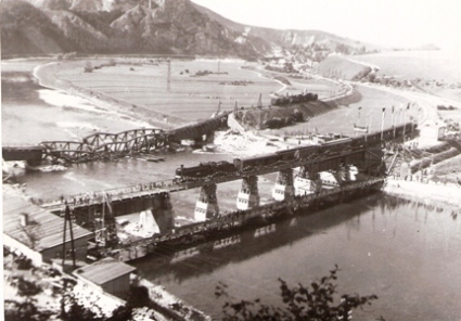  Váh pri Strečne s vyzdob. most. provizóriom na 2. koľaji a slávn. vlakom s 365.3. Pod ním cestná lávka. Zničený most na koľaji č. 1. Za ním a pod násypom už vyprostené parné rušne. Anon., 13.9.1945. 180 x 130 