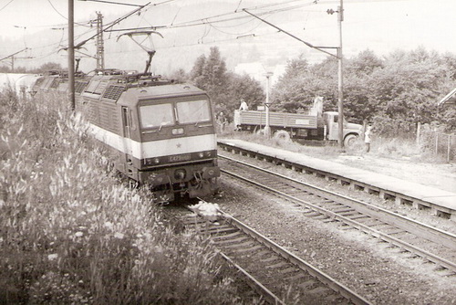  Svrčinovec - E 479.1050 s nákl. vlakom smerujúca do Čadce. Vpravo nástupište a okraj budovy zast., nákl. auto T 148. Hory. Foto: Z. Piešová, leto 1985. 130 x 90. 