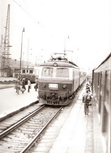  Elektrický rušeň E 499.0047 s os. vlakom vchádza k 2. perónu žst. Žilina. Pohľad z okna protiidúceho vlaku. Vzadu M 262.0. Civilisti. Foto: Z. Piešová, apríl 1985. 90 x 130 