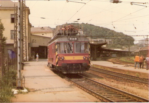  Bratislava hl. st. M 153.0074 na hranici 1. a 6. perónu. Časť priečelia výpr. budovy, pri 3. peróne os. súprava s poschod. vozňami. Robotníci v bezp. vestách. Foto: Z. Piešová, 1985. 104 x 72, COLOR 