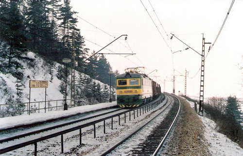  Spišský Štiavnik. Elektrický rušeň 182 124-8 s nákl. vlakom prechádza zastávkou v smere na Sp. N. Ves. Trolej. vedenie starého typu Vzadu tušiť Tatry. Foto: Z. Piešová, február 1992. 130 x 90, COLOR 