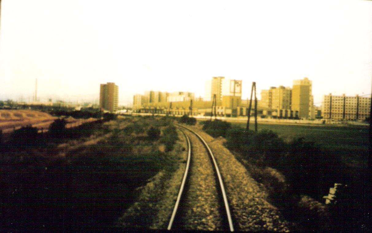  Trať Bratislava-Petržalka - Rusovce. Pohľad zo stred. dverí posled. vozňa na oblúk pri prvých petržalsk. domoch. Telegraf. tyče. Foto: M. Entner, 1990. 156 x 100, COLOR 